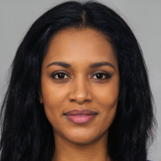 Joyful black young-adult female with long  black hair and brown eyes