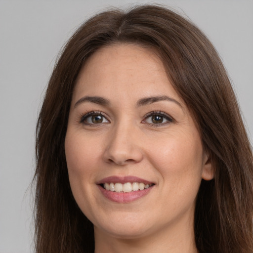 Joyful white young-adult female with long  brown hair and brown eyes