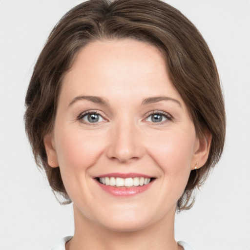 Joyful white young-adult female with medium  brown hair and grey eyes