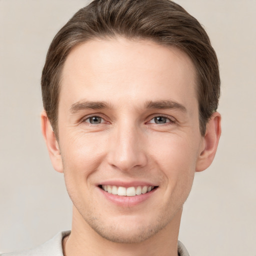 Joyful white young-adult male with short  brown hair and grey eyes