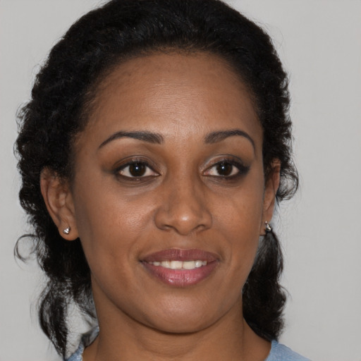 Joyful black young-adult female with long  brown hair and brown eyes