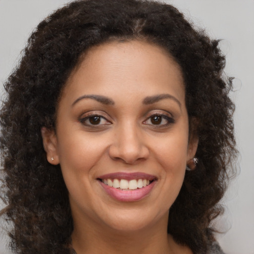 Joyful black young-adult female with long  brown hair and brown eyes