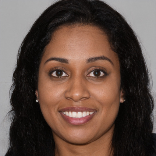 Joyful black young-adult female with long  black hair and brown eyes