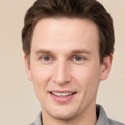 Joyful white young-adult male with short  brown hair and grey eyes