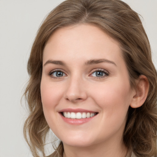 Joyful white young-adult female with long  brown hair and blue eyes