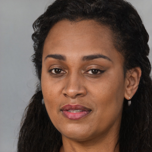 Joyful black young-adult female with long  brown hair and brown eyes