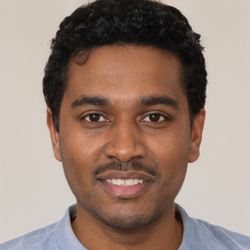 Joyful black young-adult male with short  black hair and brown eyes