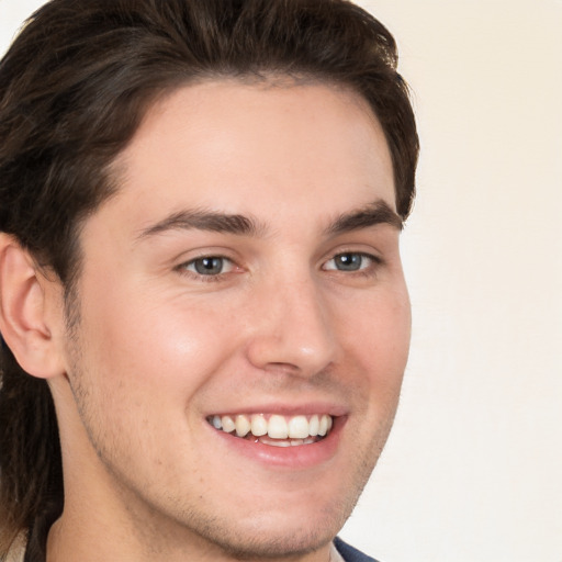 Joyful white young-adult male with long  brown hair and brown eyes