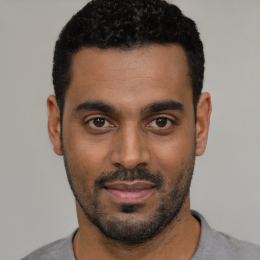 Joyful black young-adult male with short  black hair and brown eyes