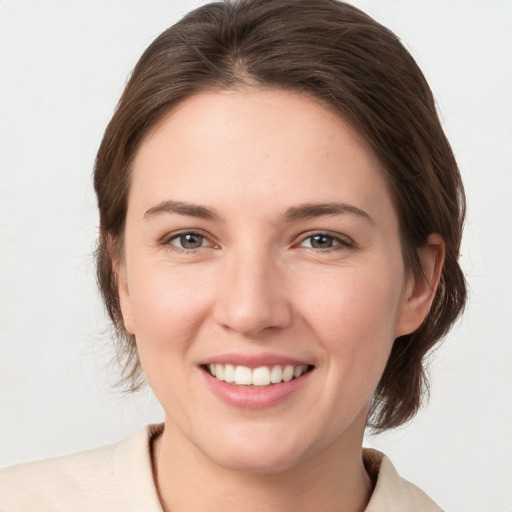 Joyful white young-adult female with medium  brown hair and grey eyes