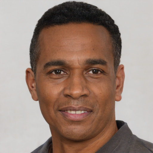 Joyful black adult male with short  black hair and brown eyes