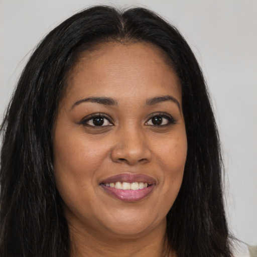 Joyful black young-adult female with long  brown hair and brown eyes