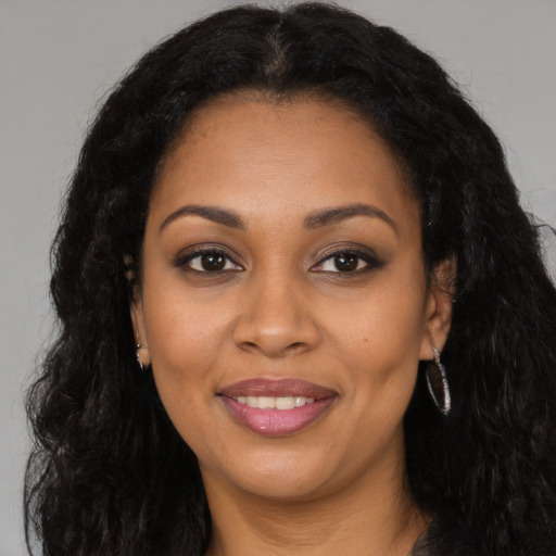 Joyful black young-adult female with long  brown hair and brown eyes