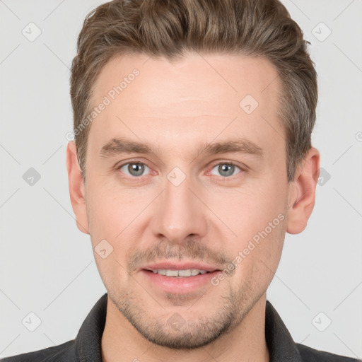 Joyful white young-adult male with short  brown hair and grey eyes