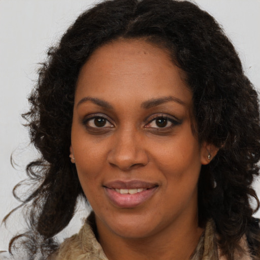 Joyful black young-adult female with long  brown hair and brown eyes