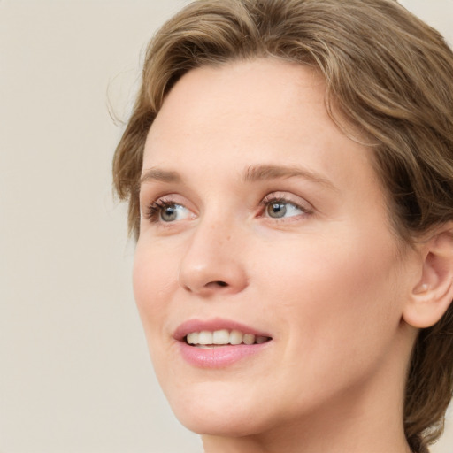 Joyful white young-adult female with medium  brown hair and green eyes