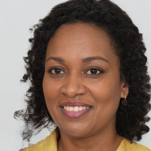 Joyful black adult female with long  brown hair and brown eyes