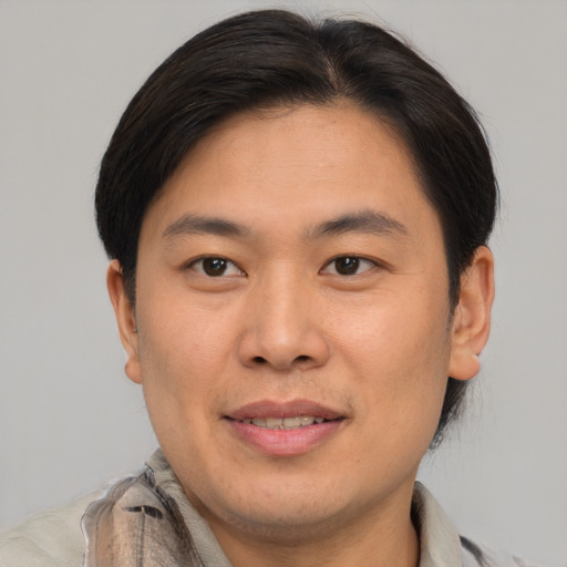 Joyful asian young-adult male with short  brown hair and brown eyes