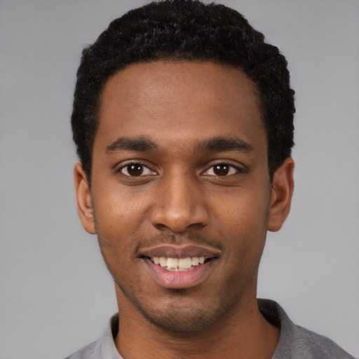 Joyful black young-adult male with short  black hair and brown eyes
