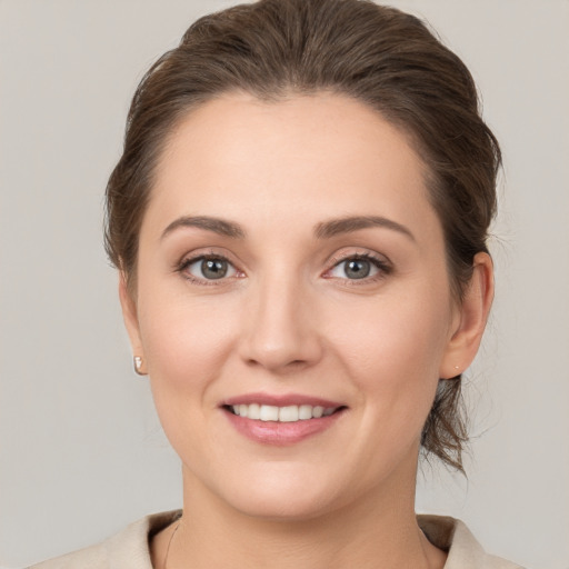 Joyful white young-adult female with medium  brown hair and grey eyes