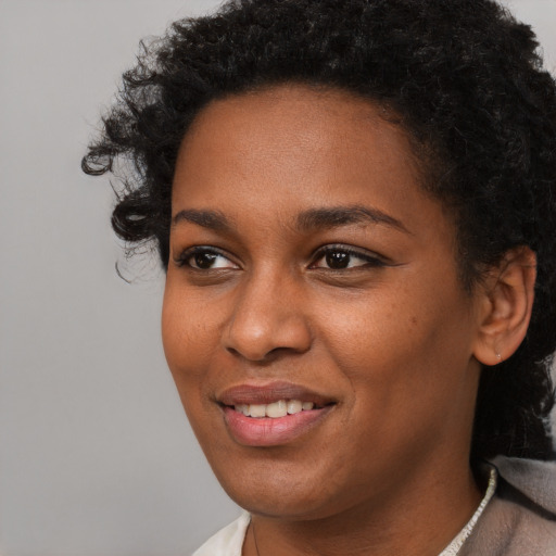Joyful black young-adult female with short  black hair and brown eyes