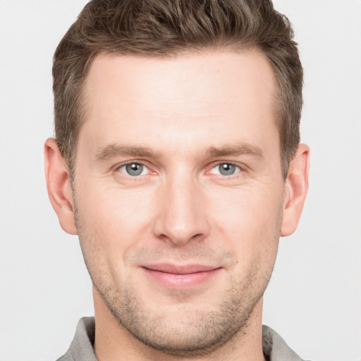 Joyful white young-adult male with short  brown hair and grey eyes