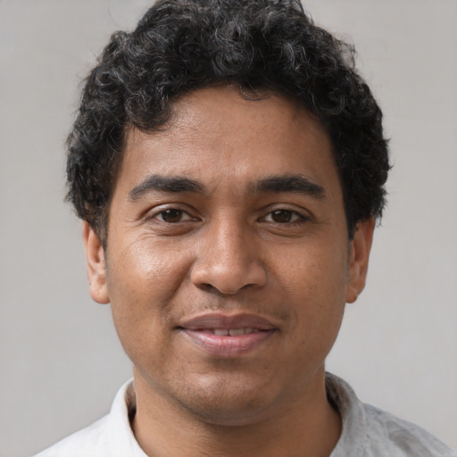 Joyful latino young-adult male with short  brown hair and brown eyes
