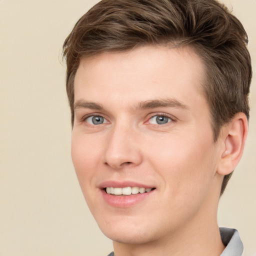 Joyful white young-adult male with short  brown hair and grey eyes