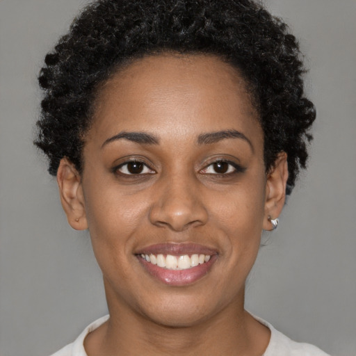 Joyful black young-adult female with short  black hair and brown eyes