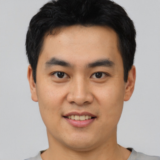 Joyful asian young-adult male with short  black hair and brown eyes