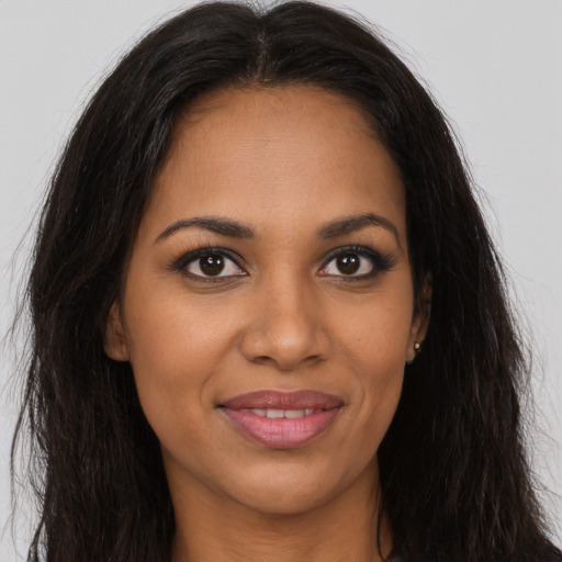 Joyful black young-adult female with long  brown hair and brown eyes