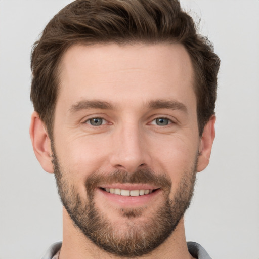 Joyful white young-adult male with short  brown hair and grey eyes