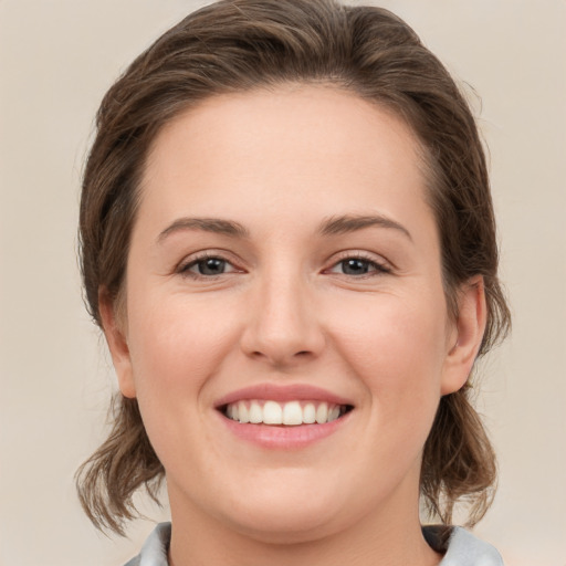 Joyful white young-adult female with medium  brown hair and grey eyes