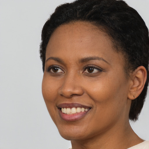 Joyful black young-adult female with short  black hair and brown eyes