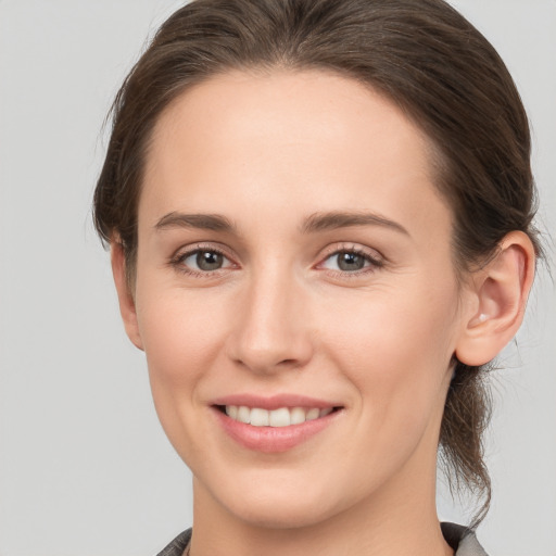 Joyful white young-adult female with medium  brown hair and grey eyes