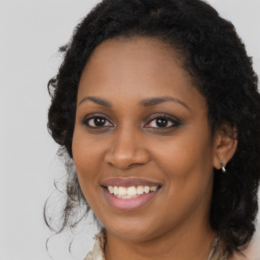 Joyful black young-adult female with long  brown hair and brown eyes