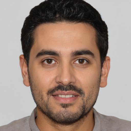 Joyful latino young-adult male with short  black hair and brown eyes