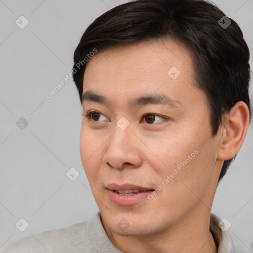 Joyful asian young-adult male with short  brown hair and brown eyes