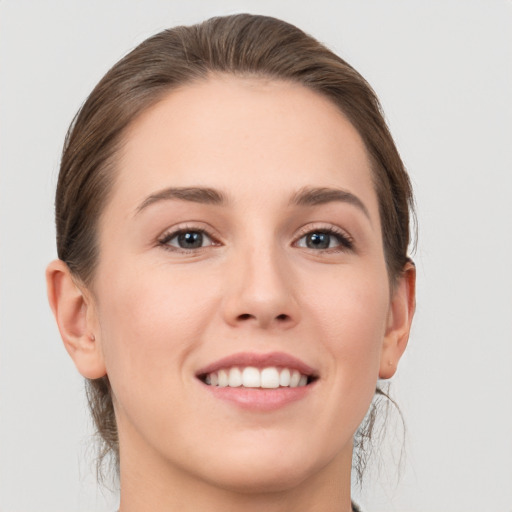 Joyful white young-adult female with medium  brown hair and grey eyes