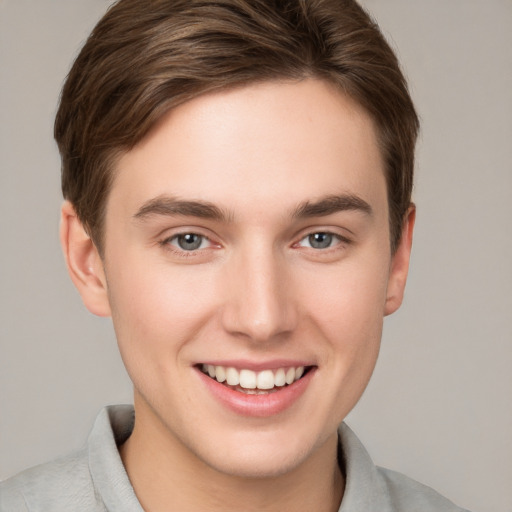 Joyful white young-adult male with short  brown hair and grey eyes