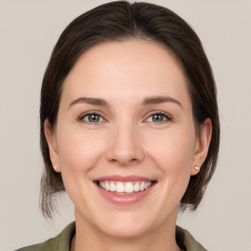 Joyful white young-adult female with medium  brown hair and grey eyes