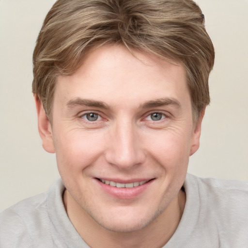 Joyful white young-adult male with short  brown hair and grey eyes