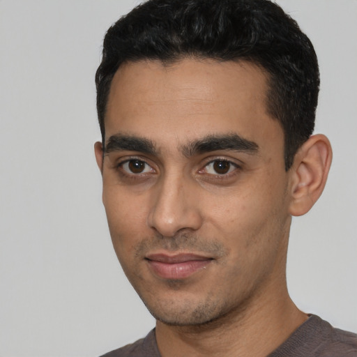 Joyful latino young-adult male with short  black hair and brown eyes