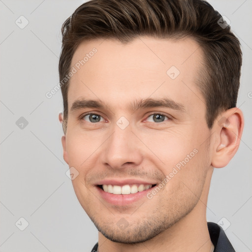 Joyful white young-adult male with short  brown hair and grey eyes