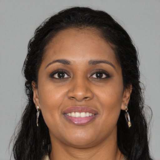 Joyful black young-adult female with long  brown hair and brown eyes