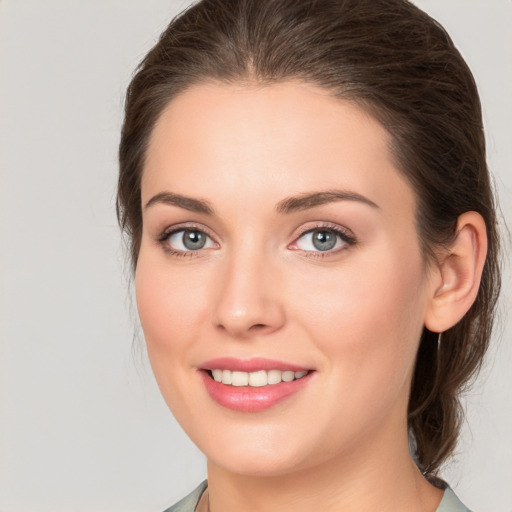 Joyful white young-adult female with medium  brown hair and grey eyes