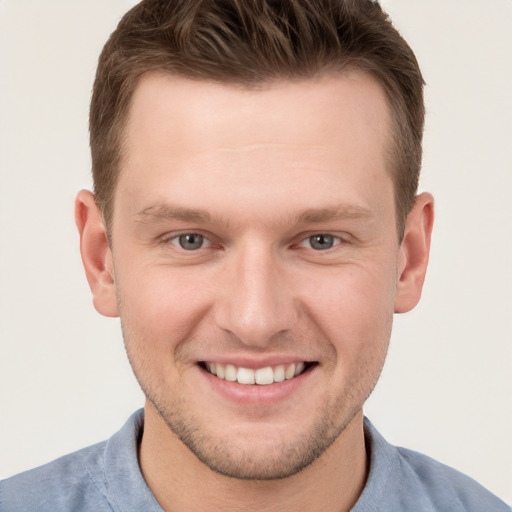 Joyful white young-adult male with short  brown hair and grey eyes