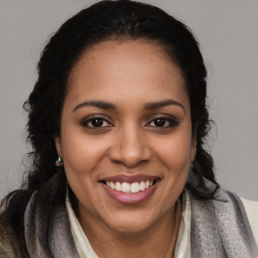Joyful black young-adult female with long  brown hair and brown eyes