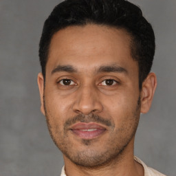 Joyful latino young-adult male with short  black hair and brown eyes