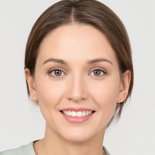 Joyful white young-adult female with medium  brown hair and grey eyes